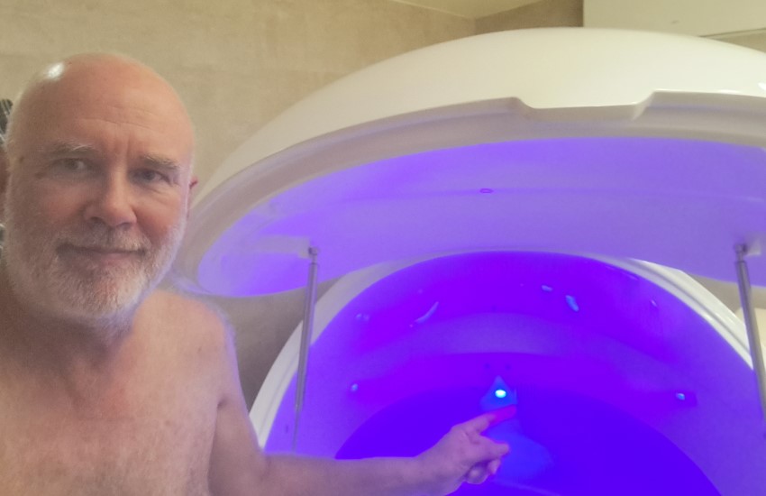 Selfie with my birthday float tank, lid open and purple-blue light on